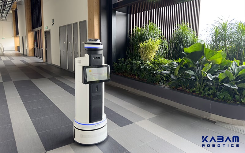 Indoor KABAM security robot patrolling near a garden area